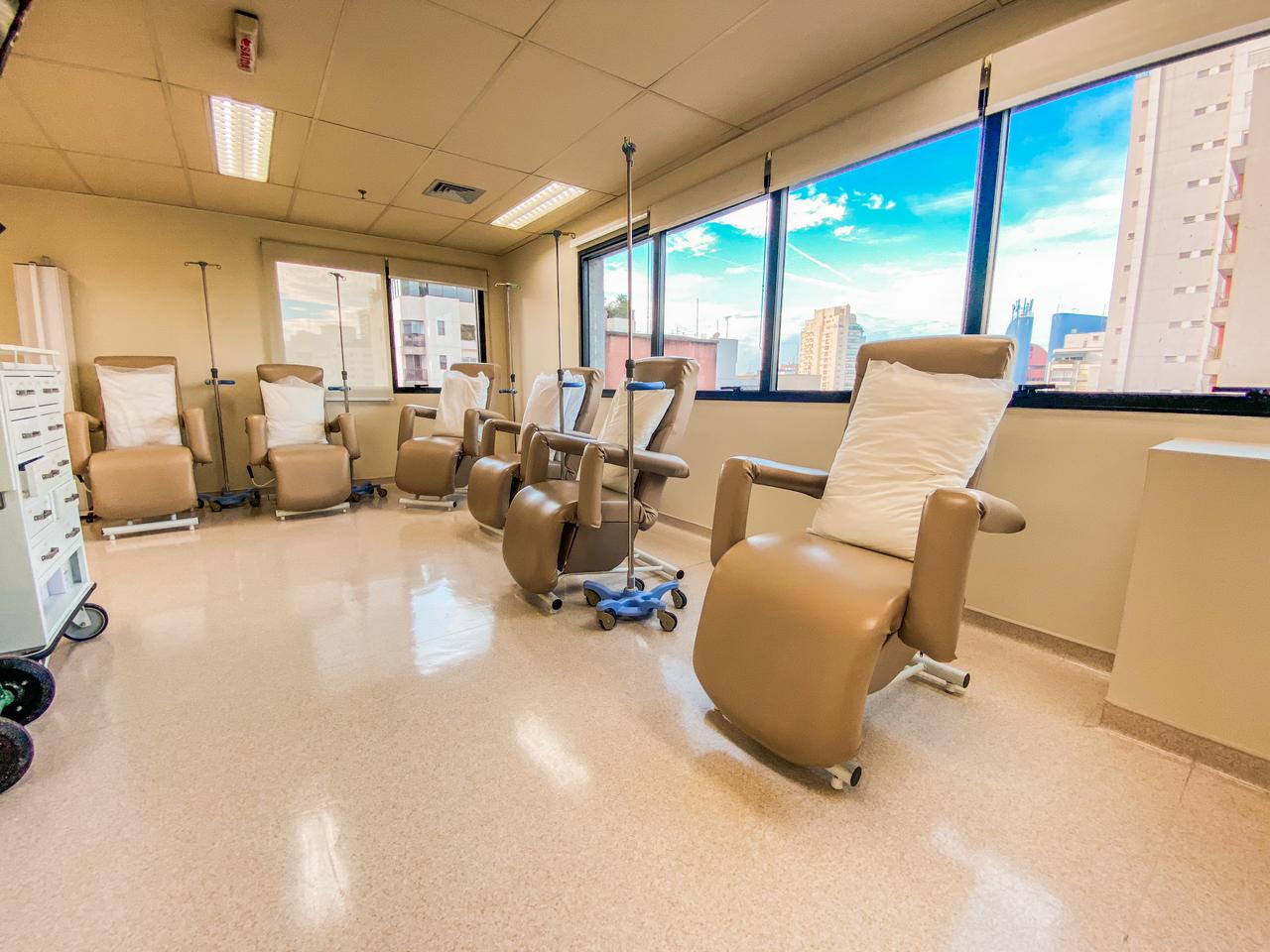 Sala de atendimento da São Paulo Oncologia Clínica, com poltronas de infusão e janelas com vista para o bairro do Paraíso